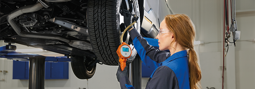 A Subaru technician checking tire pressure. | Glassman Subaru in Southfield MI